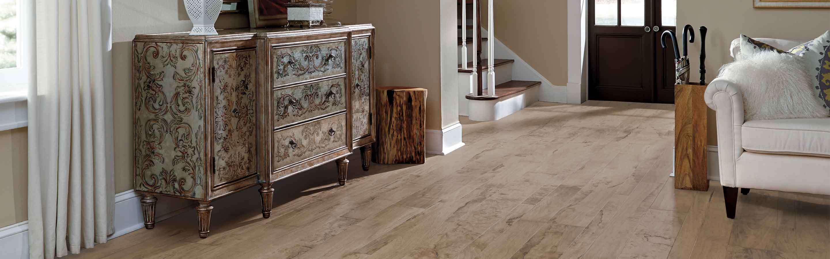 entryway into living room with distressed hardwood floors, white couch and vintage sideboard